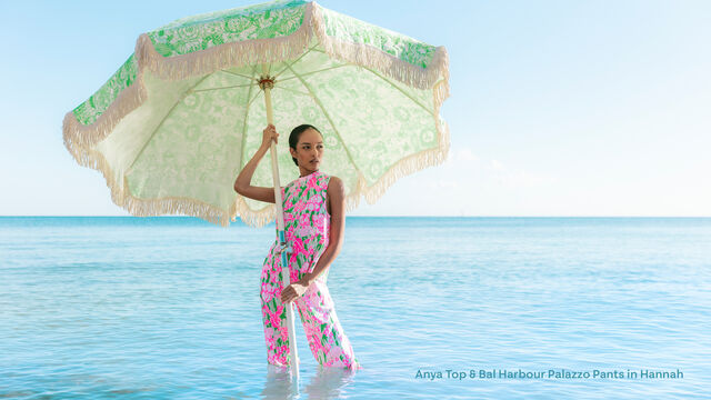 Model wearing matching set posing in ocean with beach umbrella